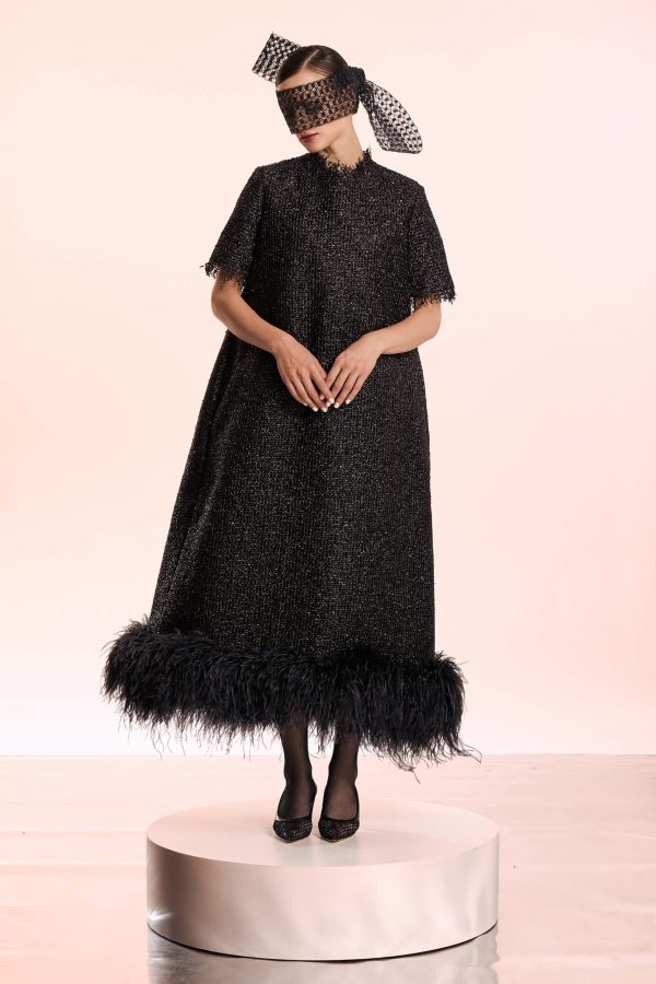 The silver thread inserted into the black fabric make this dress sparkle like a constellation. The A-line shape of the dress is due to the crinoline lining that supports the dress's harmonious form. At the bottom, it has a finish of luxurious feathers.