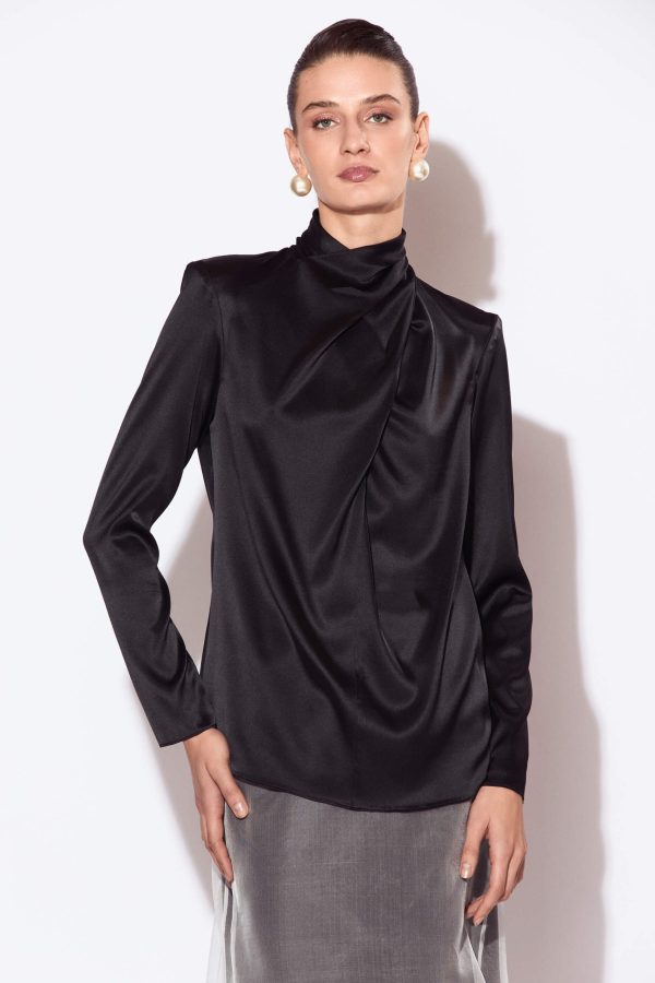 The front of the blouse features a slit in the center seam that continues into a crossover draped detail. Is shaped with shoulder darts and  has a center seam at the back. The blouse has a back keyhole opening and a stand collar with a button and rouleau loop closure.