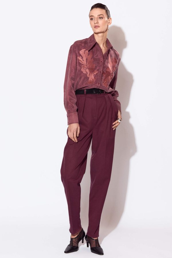 A pair of semi-fitted trousers with a straight silhouette, tapered towards the hem. The front features two soft pleats on each side at the waistline directed towards the center front. The waistband has topstitched belt loops, its top edge sits on the natural waistline and it fastens with a hook and eye. This pair of trousers is below ankle length.