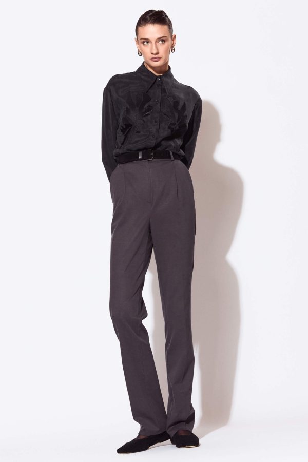 A pair of semi-fitted trousers with a straight silhouette, tapered towards the hem. The front features two soft pleats on each side at the waistline directed towards the center front. The waistband has topstitched belt loops, its top edge sits on the natural waistline and it fastens with a hook and eye. This pair of trousers is below ankle length.