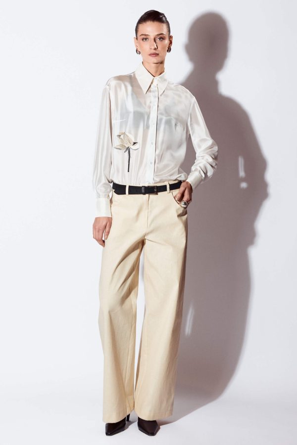 Slightly-loose fit, straight full-length women’s trousers. The front pieces are designed with scoop pockets and the back pieces are designed with an attached yoke and tailored patch pockets. Under the back pocket are embroidered with the platycerium plant . The trousers are fastened with a zipper.