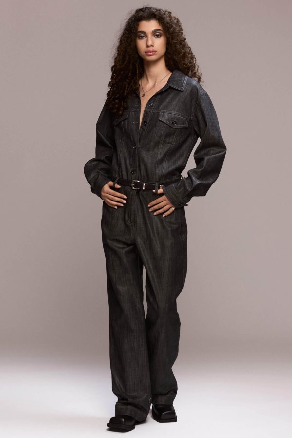 This black demin boilersuit is a long-sleeved, full-length garment with a straight leg cut, has a front closure with buttons and zipper for the trousers. It features patch pockets on both sides of the chest and 4 functional ones, two in front and other two on the back of the trousers. Its fit is comfortable yet flattering, making it a versatile wardrobe piece. Wear it on it's own or with a contrasting belt.
