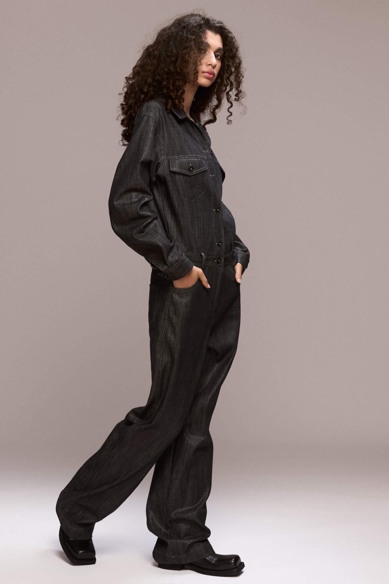 This black demin boilersuit is a long-sleeved, full-length garment with a straight leg cut, has a front closure with buttons and zipper for the trousers. It features patch pockets on both sides of the chest and 4 functional ones, two in front and other two on the back of the trousers. Its fit is comfortable yet flattering, making it a versatile wardrobe piece. Wear it on it's own or with a contrasting belt.