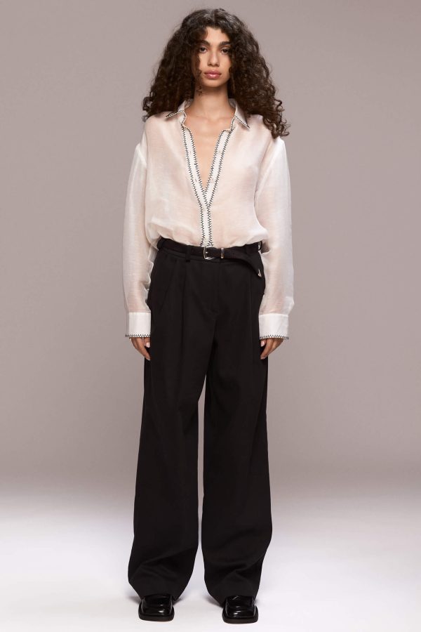 The black classic trousers offer a blend of tailoring and a relaxed fit, perfect for versatile styling. They feature front pleat details and belt loops, with front pockets and a single back welt pocket on the right side. The trousers have a fly front zipper closure and are floor length.