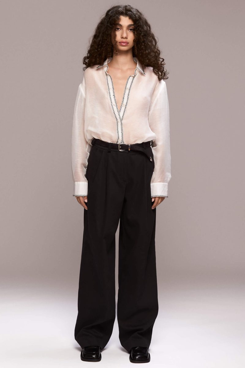 The black classic trousers offer a blend of tailoring and a relaxed fit, perfect for versatile styling. They feature front pleat details and belt loops, with front pockets and a single back welt pocket on the right side. The trousers have a fly front zipper closure and are floor length.