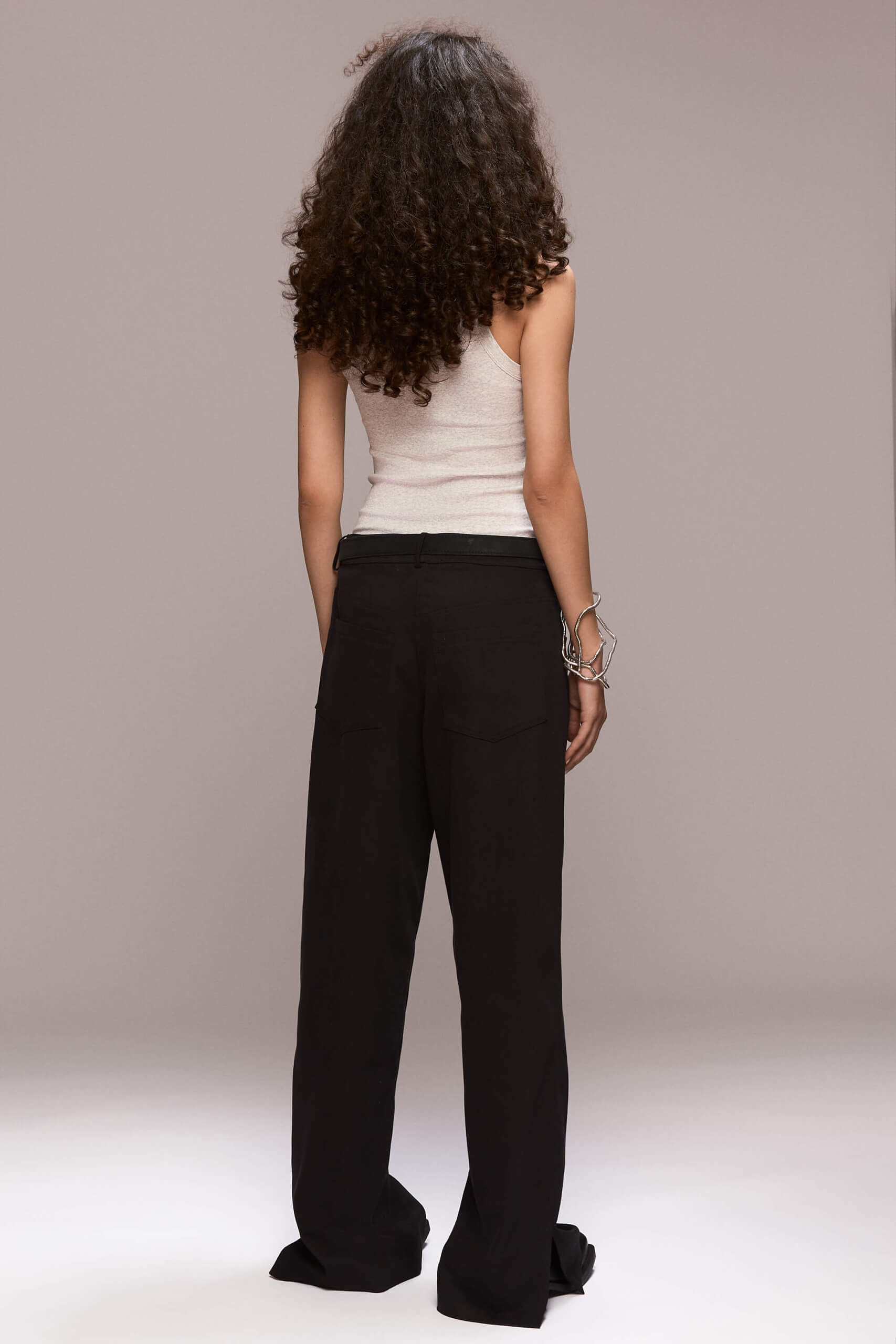 The side splits black trousers is a pair of straight-cut trousers, with bottom side splits. The trousers are floor-length, with functional pockets in the side seams and also two functional back pockets and have a fly front zipper closure.