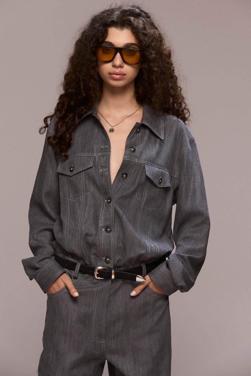 This gray demin boilersuit is a long-sleeved, full-length garment with a straight leg cut, has a front closure with buttons and zipper for the trousers. It features patch pockets on both sides of the chest and 4 functional ones, two in front and other two on the back of the trousers. Its fit is comfortable yet flattering, making it a versatile wardrobe piece. Wear it on it's own or with a contrasting belt.