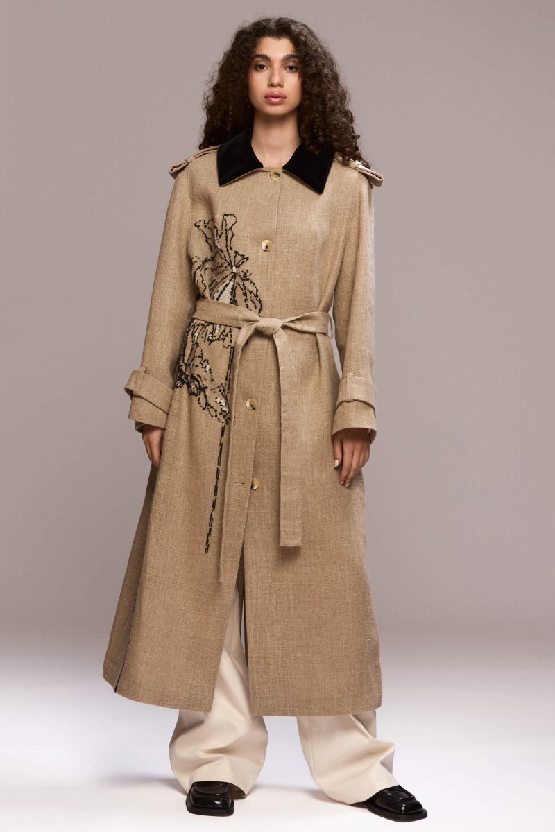 Beige maxi coat with a striking black velvet collar and handmade floral embroidery. The coat is designed for a relaxed fit and icludes a matching tie belt, for a defined silhouette.