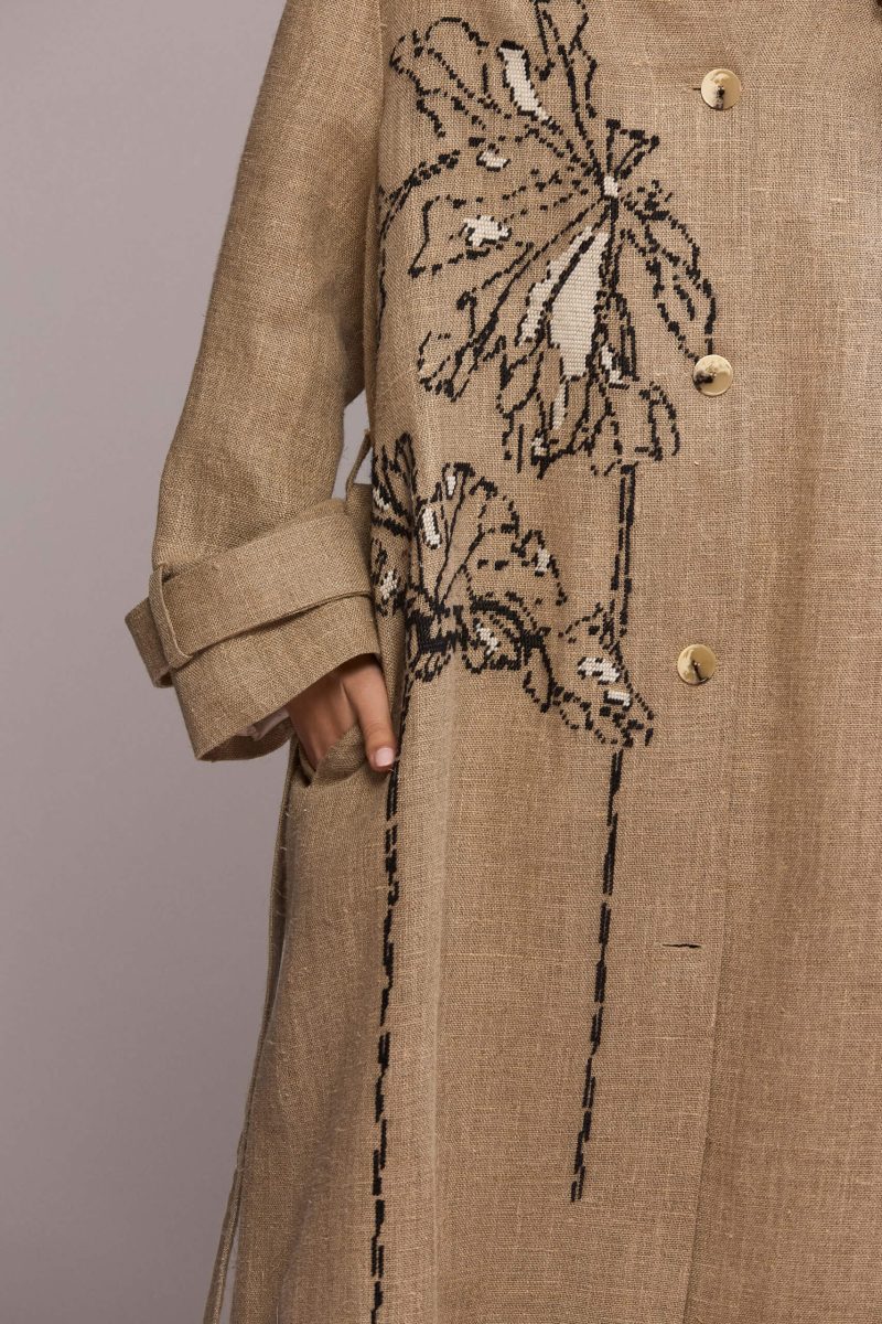 Beige maxi coat with a striking black velvet collar and handmade floral embroidery. The coat is designed for a relaxed fit and icludes a matching tie belt, for a defined silhouette.
