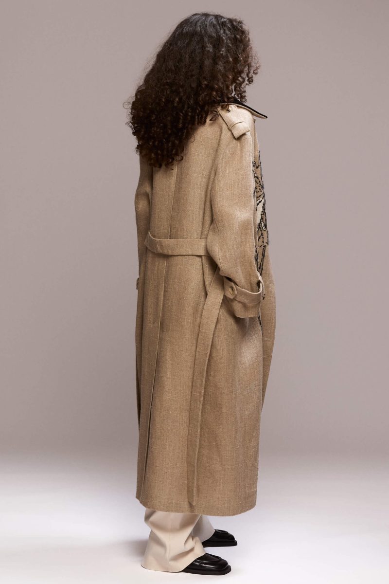 Beige maxi coat with a striking black velvet collar and handmade floral embroidery. The coat is designed for a relaxed fit and icludes a matching tie belt, for a defined silhouette.