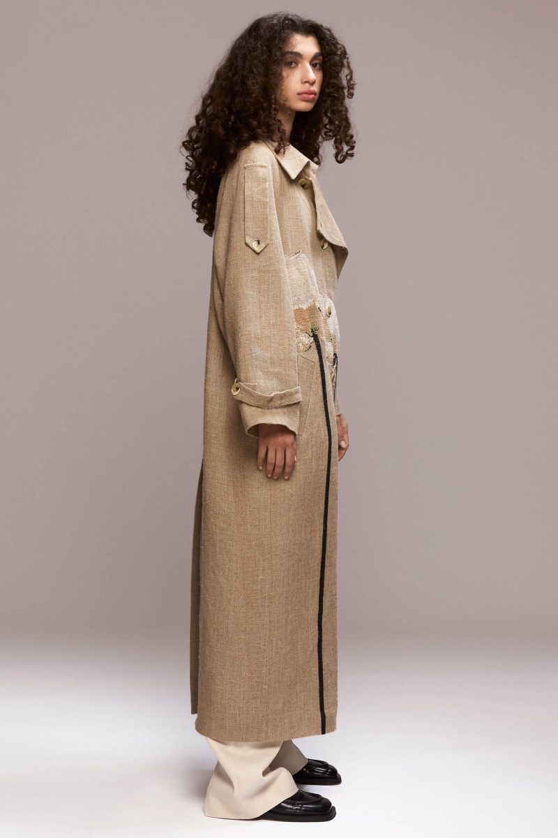 This long beige coat is made of 100% and it features a handmade lotus flowers. It also has a detachable belt.