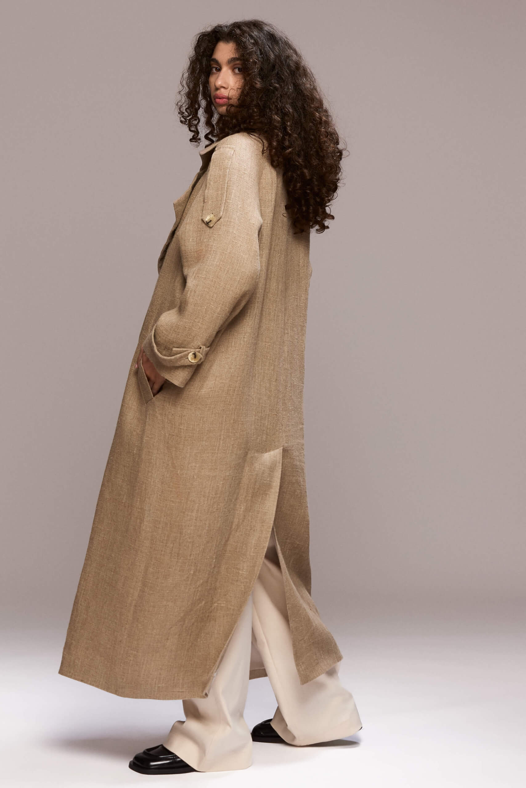 This long beige coat is made of 100% and it features a handmade lotus flowers. It also has a detachable belt.