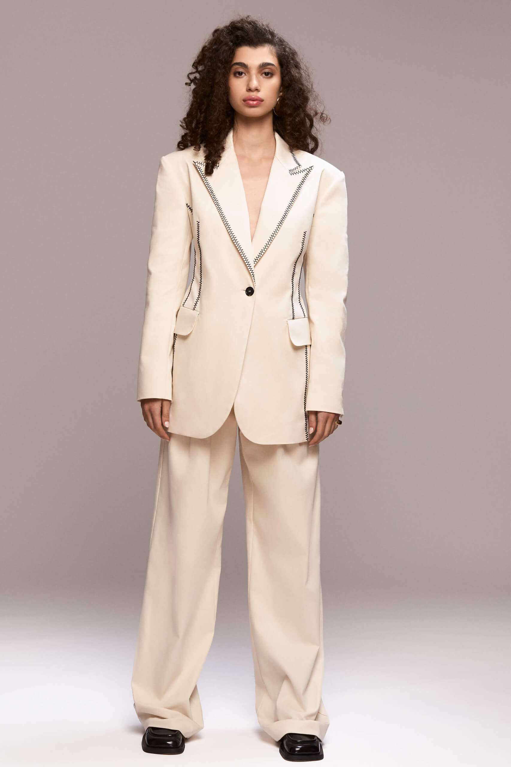 single-button front closure, padded shoulders and functional pockets. It can be worn with a matching trousers for a total look.