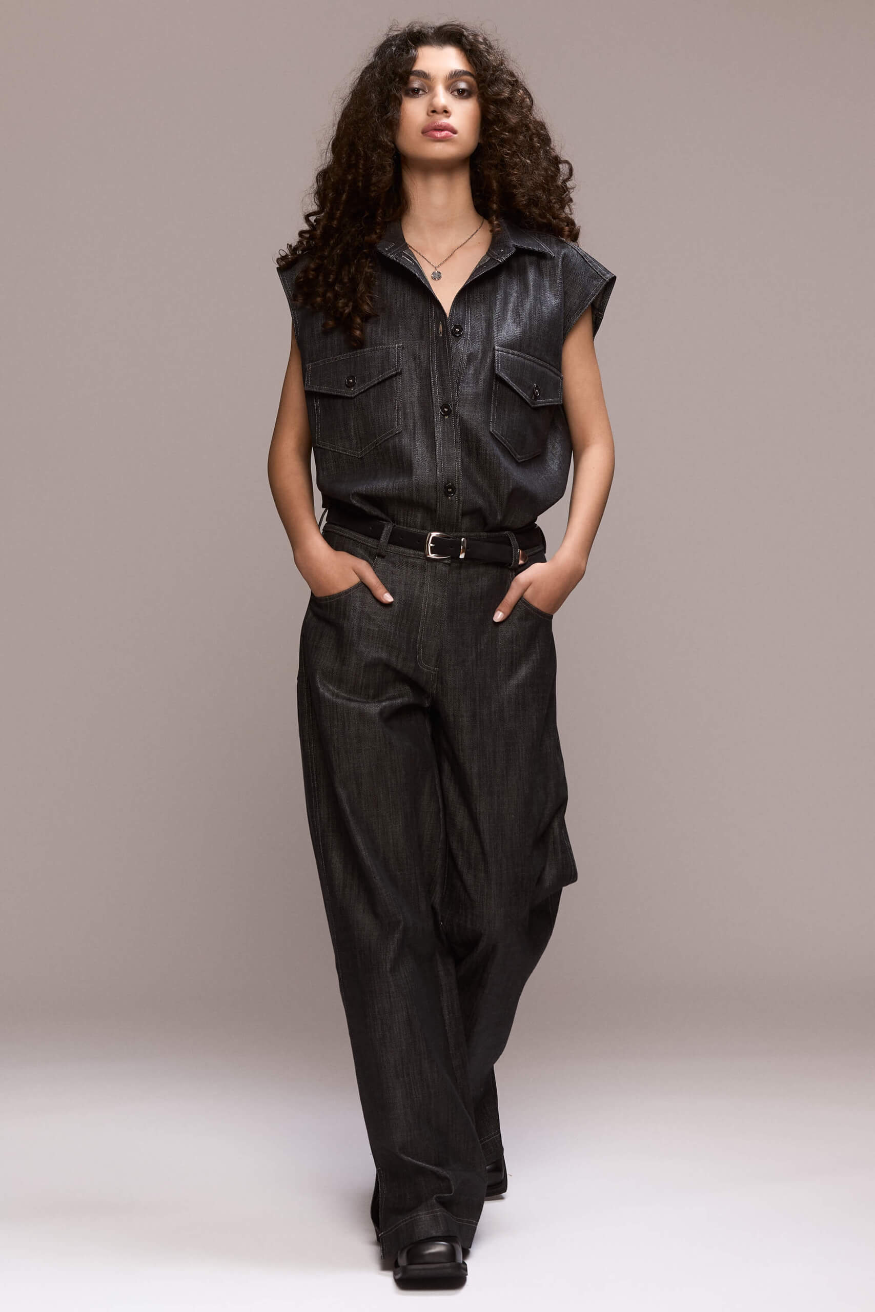 These black wide-leg trousers feature front pleats, which give them a comfortable and flowy fit. They are full length, with front pockets and one single back pocket on the right side. There is a fly front zipper closure. Wear them with our matching black sleeveless shirt for a total look.