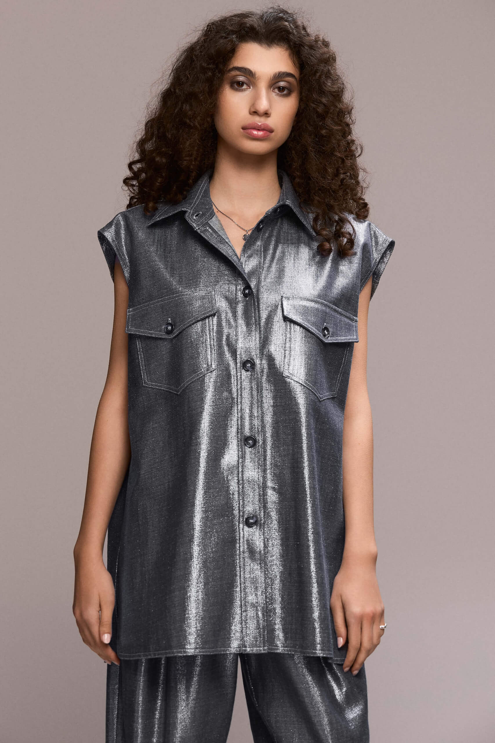 A sleveless, oversized button-down shirt featuring a collared neckline and dual chest pockets, this piece gives a distinctly modern and eye-catching appearance. Wear it with our matching wide leg trousers for a full statement look.