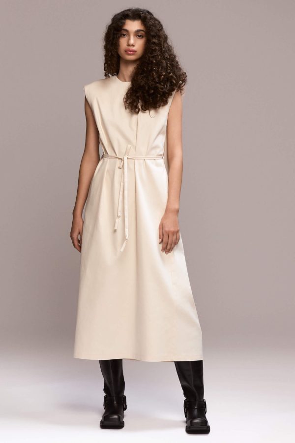 Off-white sleeveless, loose-fit maxi dress designed to flow on the body, with beautiful back pleats and structured padded shoulders. The dress includes a removable self-tie belt to cinch the waist and side pockets.