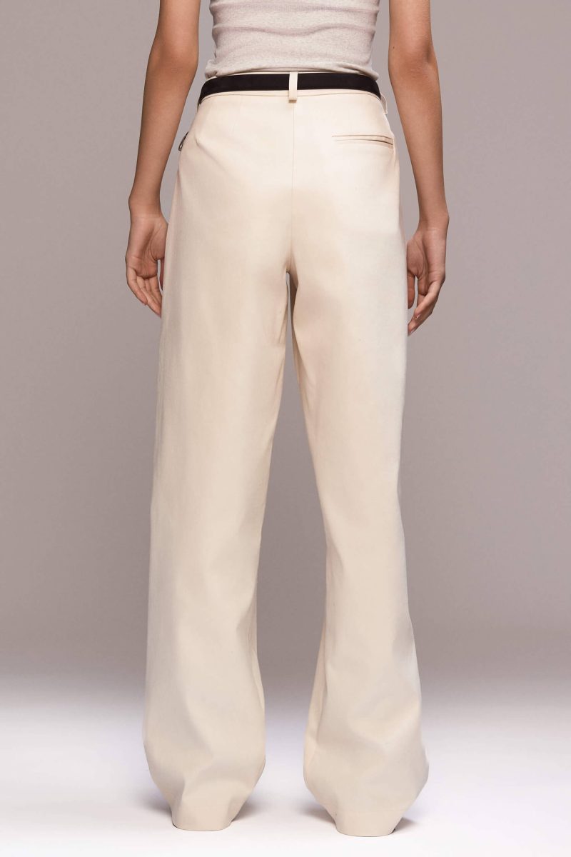 These wide-leg ivory trousers feature front pleats, which give them a relaxed silhouette. They have full length, front pockets and one single back pocket on the right side. There is a fly front zipper closure.