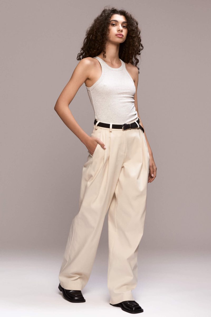 These wide-leg ivory trousers feature front pleats, which give them a relaxed silhouette. They have full length, front pockets and one single back pocket on the right side. There is a fly front zipper closure.