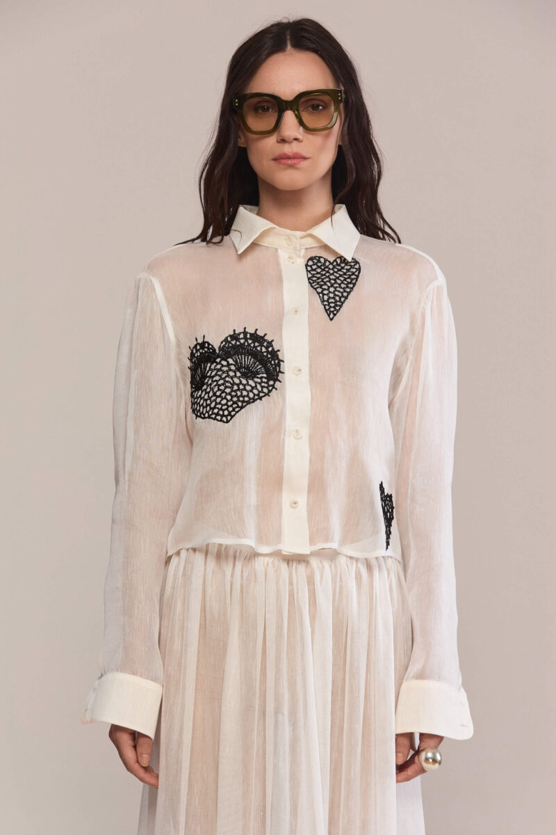 Crafted from pure silk, with a classic button-down, this elegant long sleeved shirt with a relaxed fit has a beautiful black lace hearts embroidery. Wear it with our matching maxi white silk skirt for a casual yet sophisticated look.