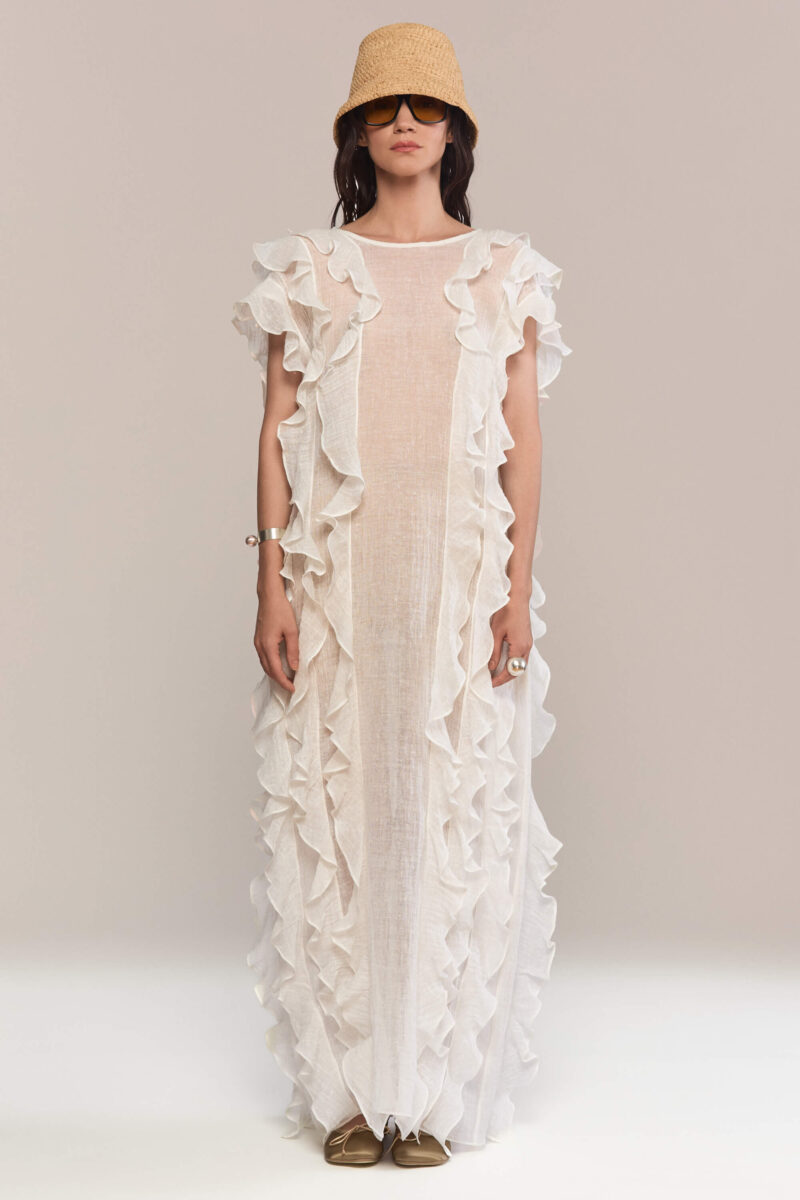 The frilled maxi dress has a loose fit, with a sleeveless design and a round neckline. It features layered ruffles on both the front and back giving it a fluid and feminine look. It is the perfect choice for summer events, or a bohemian-inspired look.