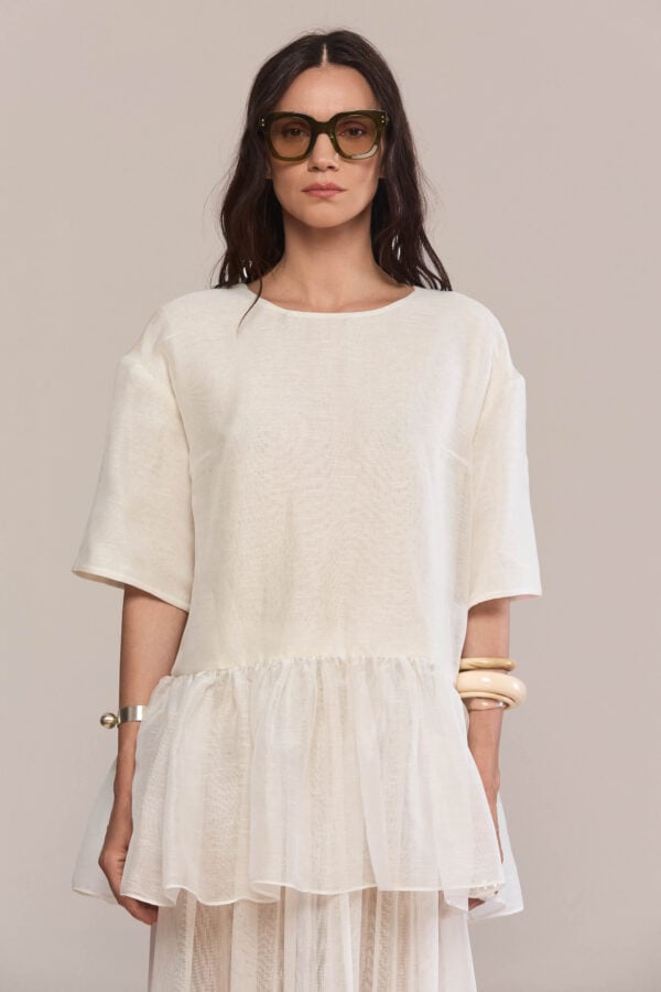 This relaxed and airy top made of 100% silk is a versatile summer staple. The dropped waist falls into a voluminous peplum hem with soft gathers, adding subtle texture and movement. Pair it with the matching skirt for a total look.