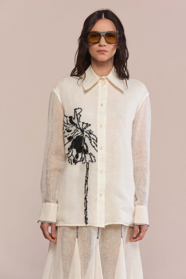 This shirt combines a modern silhouette with a classic pointed collar. Hand-embroidered black floral motif creates a statement piece in your wardrobe, while the semi-sheer fabric offers a lightweight, breathable feel with natural texture.
