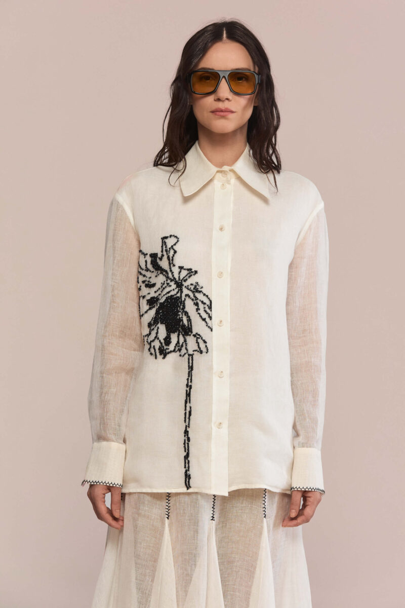 This shirt combines a modern silhouette with a classic pointed collar. Hand-embroidered black floral motif creates a statement piece in your wardrobe, while the semi-sheer fabric offers a lightweight, breathable feel with natural texture.