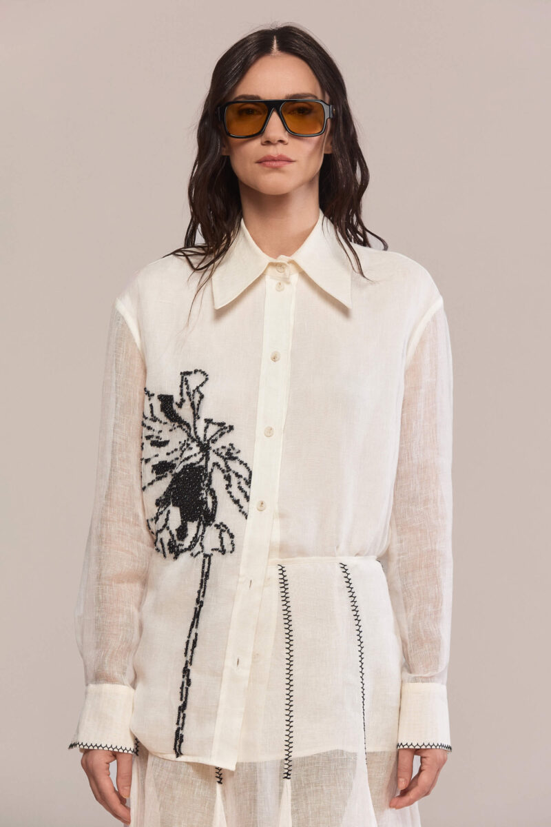 This shirt combines a modern silhouette with a classic pointed collar. Hand-embroidered black floral motif creates a statement piece in your wardrobe, while the semi-sheer fabric offers a lightweight, breathable feel with natural texture.