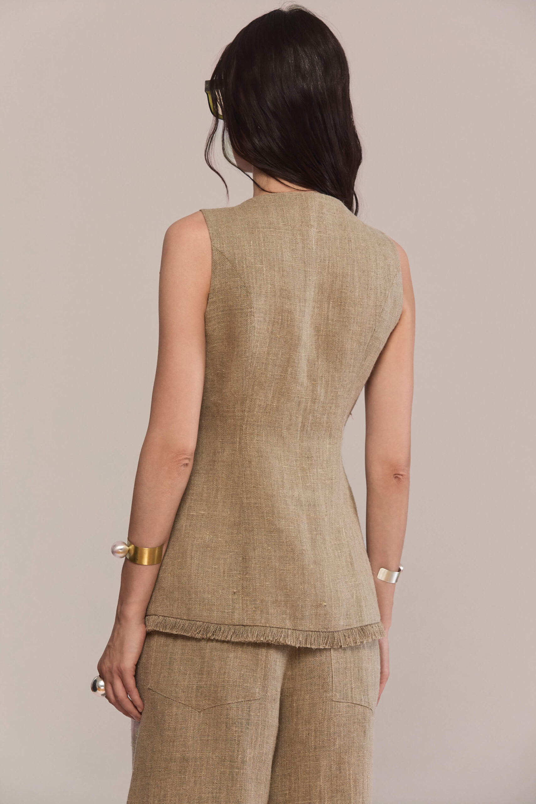 This tailored hemp vest features a structured silhouette with a high round neckline and signature front button closures. A modern cutaway hem and functional side pockets add versatility, making it perfect as a standalone top or layered over other pieces.