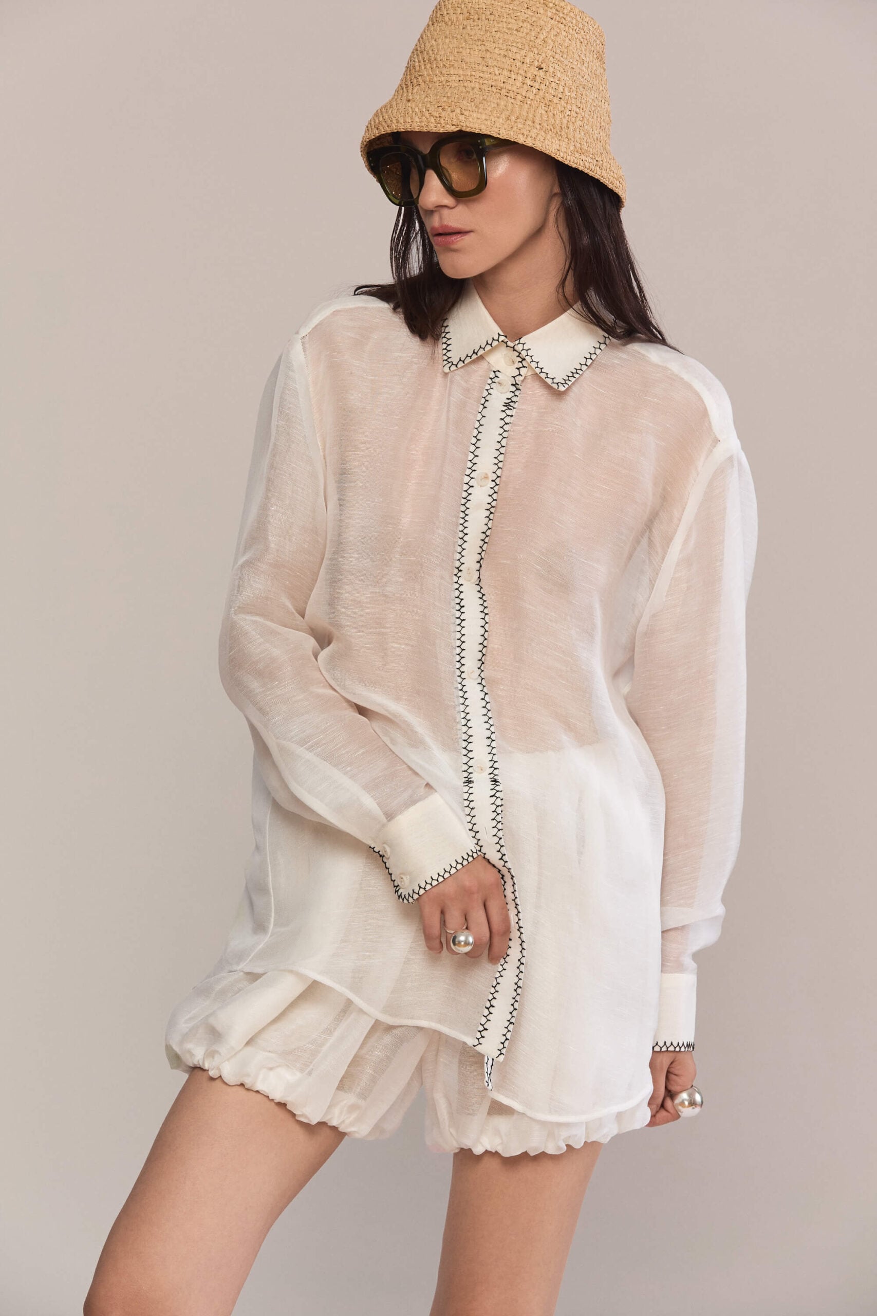 This oversized, semi-sheer shirt features a relaxed fit with long sleeves and a classic pointed collar. Black contrast hand stitch embroidery highlights the collar, front placket, and cuffs, creating a subtle, handcrafted minimalist aesthetic. Wear them with our classic black trousers for a total look.