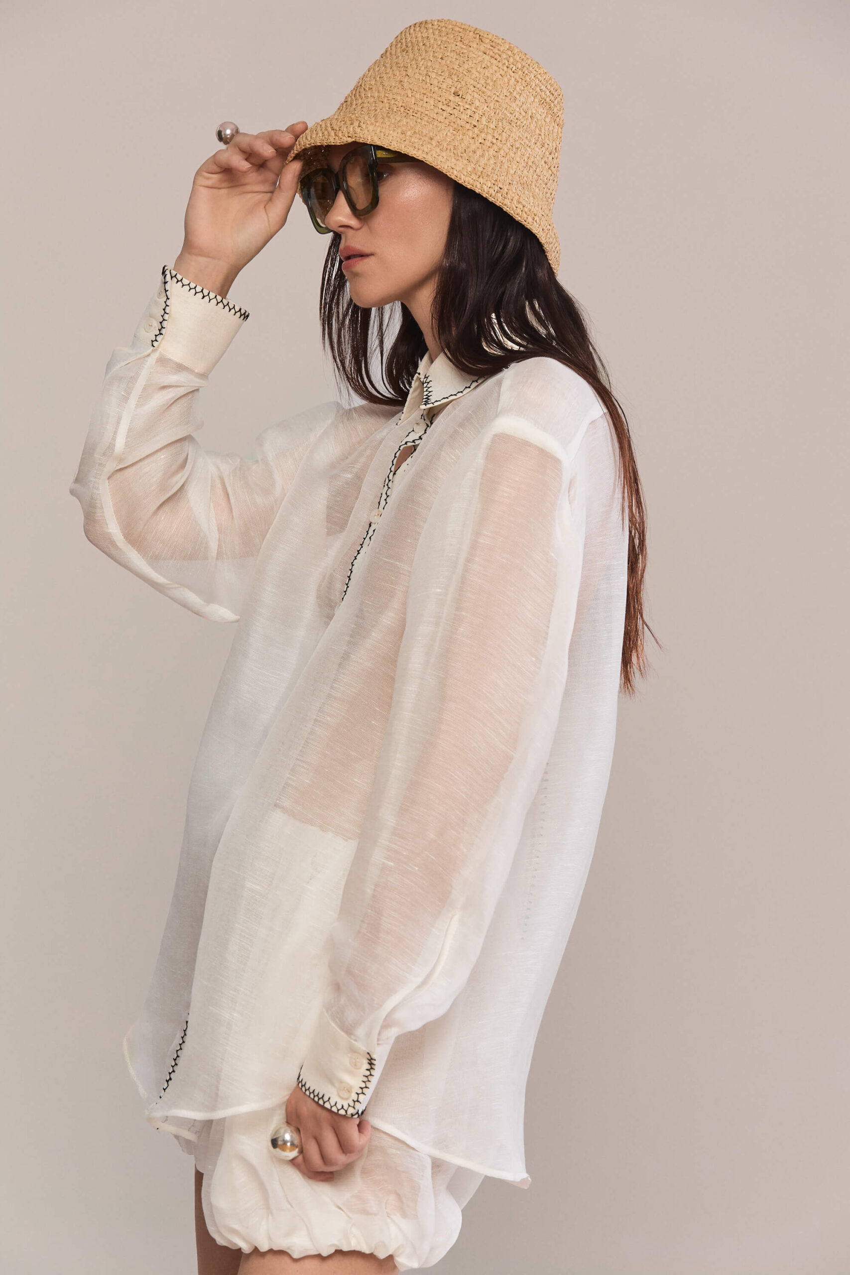 This oversized, semi-sheer shirt features a relaxed fit with long sleeves and a classic pointed collar. Black contrast hand stitch embroidery highlights the collar, front placket, and cuffs, creating a subtle, handcrafted minimalist aesthetic. Wear them with our classic black trousers for a total look.